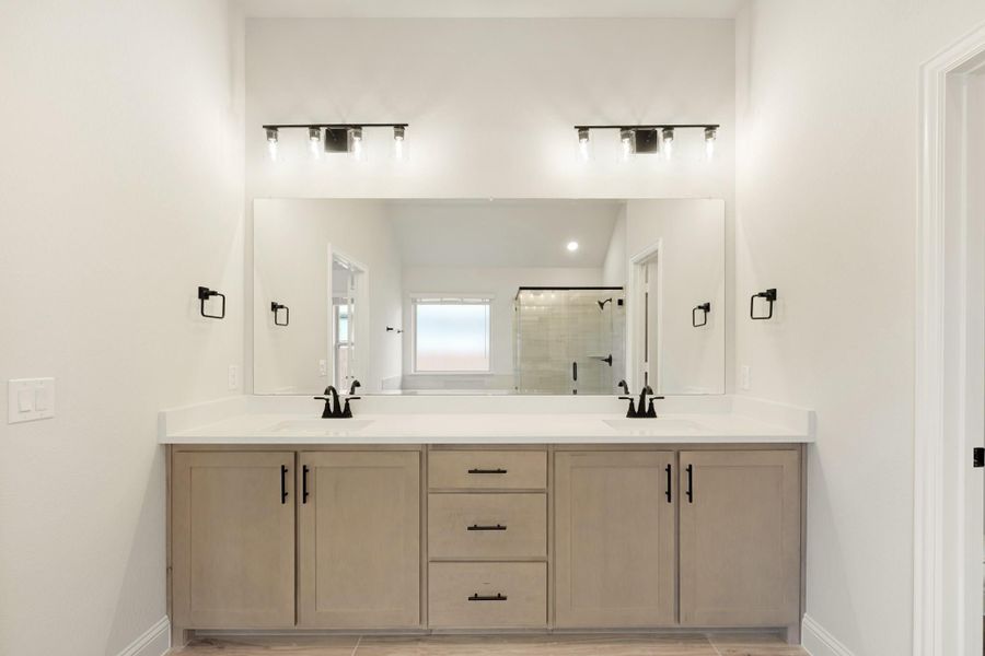 Bathroom double vanity with gray cabinets, white countertop, large mirror, and black hardware fixtures above two sinks