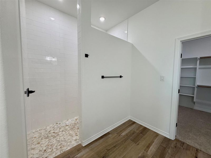 Walk-in shower with clear glass enclosure, subway tile surround, and mosaic tile flooring