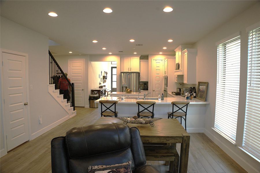 Kitchen with a kitchen breakfast bar, stainless steel refrigerator with ice dispenser, recessed lighting, light wood-type flooring, and a peninsula Kitchen with a kitchen breakfast bar, stainless steel refrigerator with ice dispenser, recessed lighting, light wood-type flooring, and a peninsula