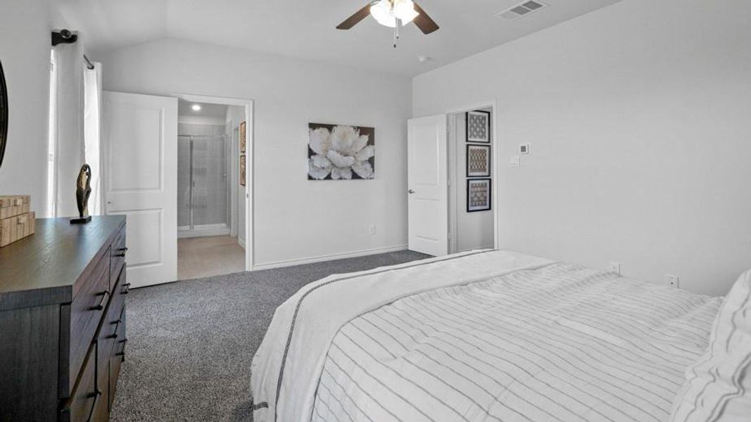 Bedroom featuring ceiling fan, vaulted ceiling, light colored carpet, and ensuite bathroom