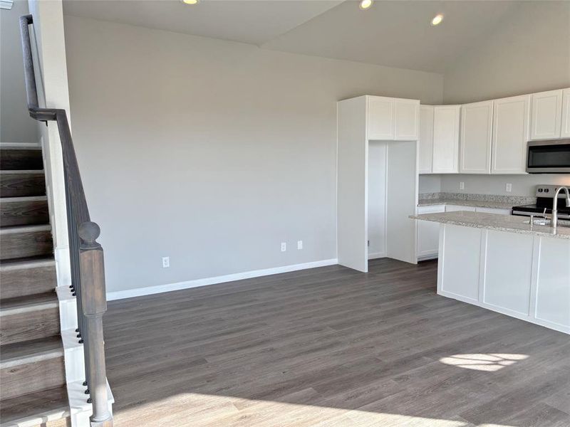 Kitchen with white cabinetry, appliances with stainless steel finishes, light stone counters, recessed lighting, and dark wood finished floors