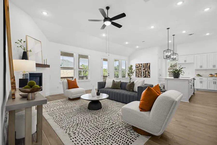 Living area featuring lofted ceiling, recessed lighting, light wood-type flooring, a glass covered fireplace, and ceiling fan