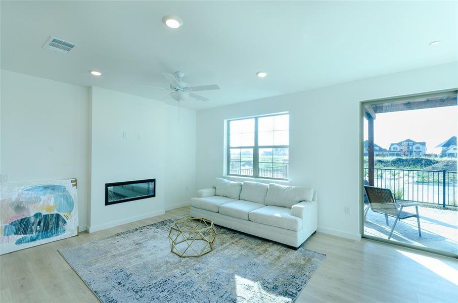Living area with a glass covered fireplace, recessed lighting, ceiling fan, and light wood-type flooring
