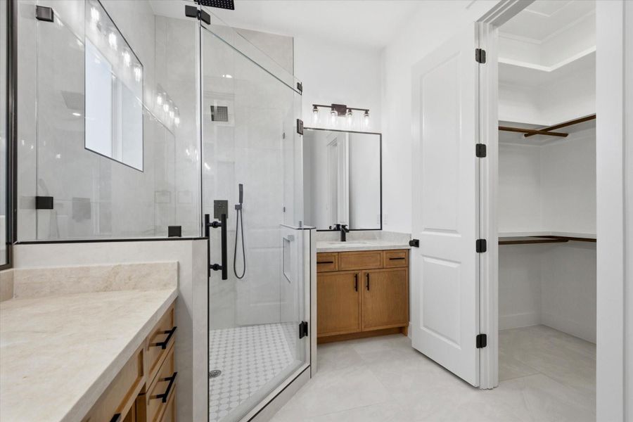 Spa-Like Luxury. Indulge in the primary bath’s custom walk-in shower with floor-to-ceiling tile, dual showerheads (including a rainfall feature), dual warm wood vanities with quartz countertops, and a seamless transition to the massive walk-in closet.
