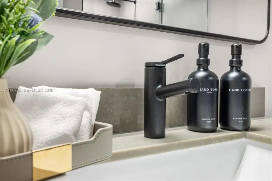Stone countertop featuring an undermount sink, a matte black single-handle faucet, and a black-framed rectangular wall mirror Stone countertop featuring an undermount sink, a matte black single-handle faucet, and a black-framed rectangular wall mirror