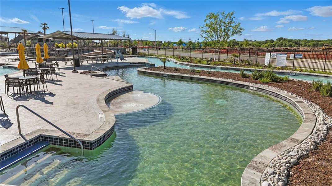 Resort-style pool area featuring a lazy river, sun shelf, and tiled spa with handrails Resort-style pool area featuring a lazy river, sun shelf, and tiled spa with handrails