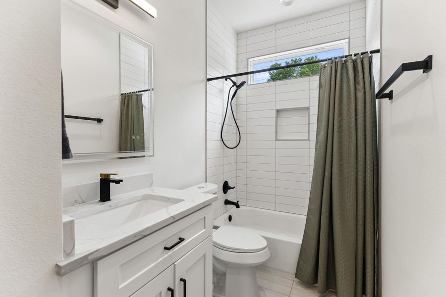 Bathroom featuring a white vanity with a rectangular undermount sink, a stone-finish countertop, and a black and gold-tone faucet