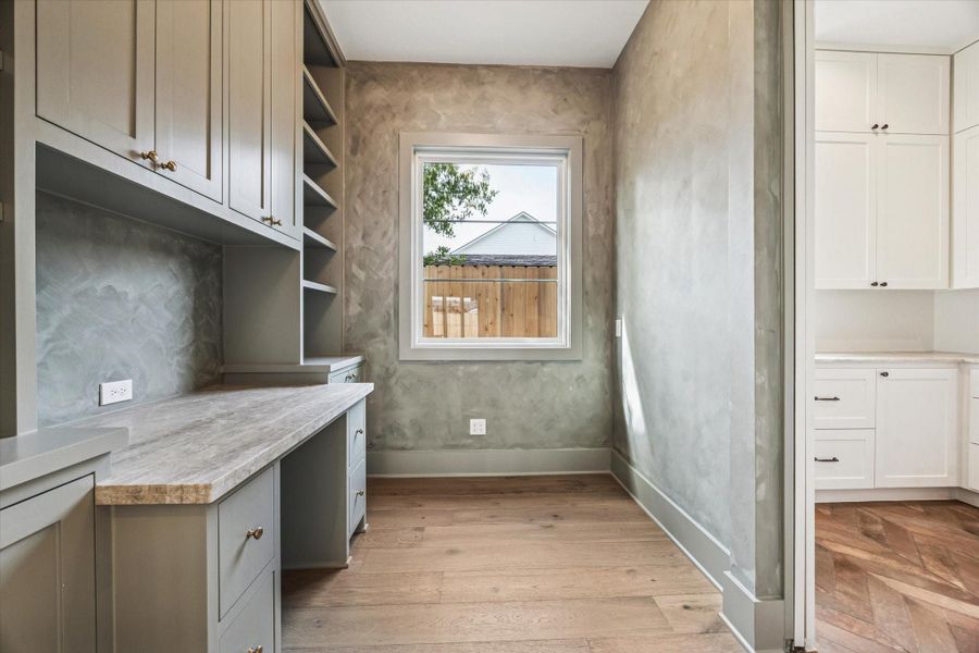 Built in workspace featuring floor to ceiling cabinetry, open shelving, and integrated desk area with designer hardware and textured accent walls, offering a dedicated home office or study nook filled with natural light in this Harvard Homes design.