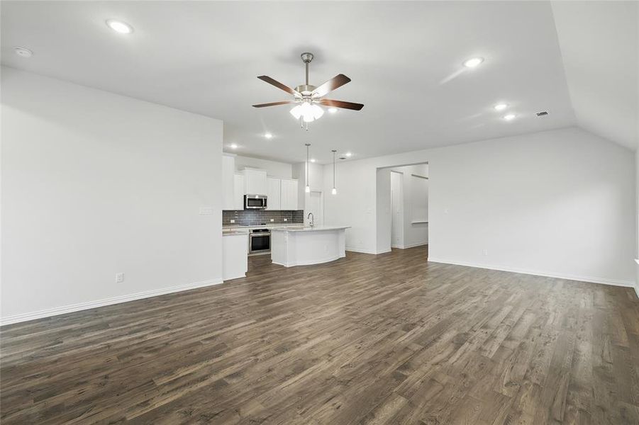 Unfurnished living room with dark wood-type flooring, a ceiling fan, baseboards, and recessed lighting Unfurnished living room with dark wood-type flooring, a ceiling fan, baseboards, and recessed lighting