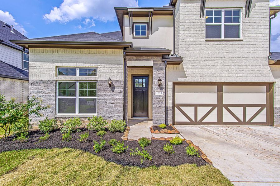 A closer look at the inviting entryway, framed by beautiful stone detailing and double coach lights. The front landscaping is freshly mulched and thoughtfully arranged for an easy-maintenance, polished look.
