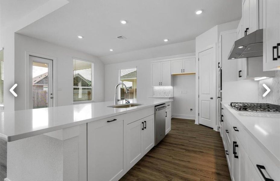 Kitchen featuring white cabinetry, dark wood-style floors, recessed lighting, an island with sink, and decorative backsplash
