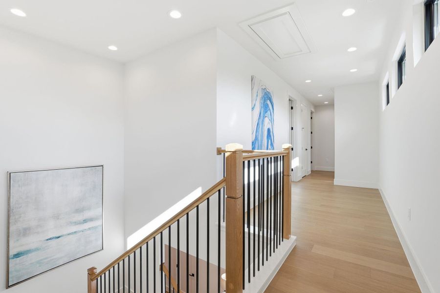 Hallway with an upstairs landing, recessed lighting, and light wood finished floors Hallway with an upstairs landing, recessed lighting, and light wood finished floors