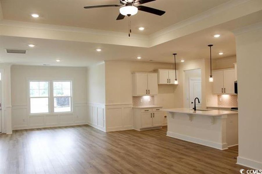 Kitchen with white cabinets, a kitchen bar, ornamental molding, recessed lighting, and dark wood-style flooring