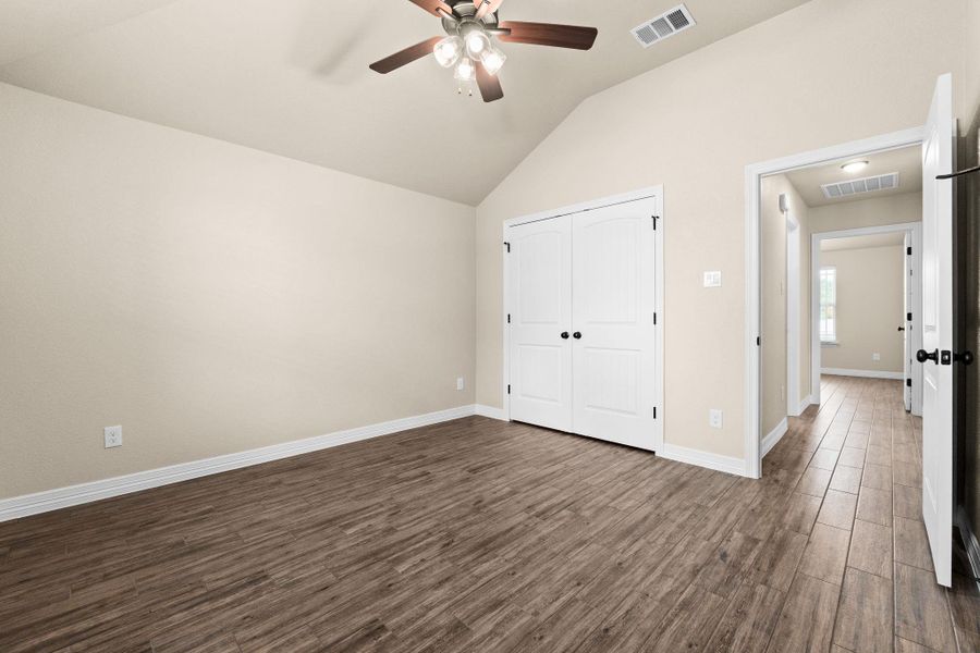 Spare room featuring dark wood like tile floors, lofted ceiling, and a ceiling fan, and a closet Spare room featuring dark wood like tile floors, lofted ceiling, and a ceiling fan, and a closet