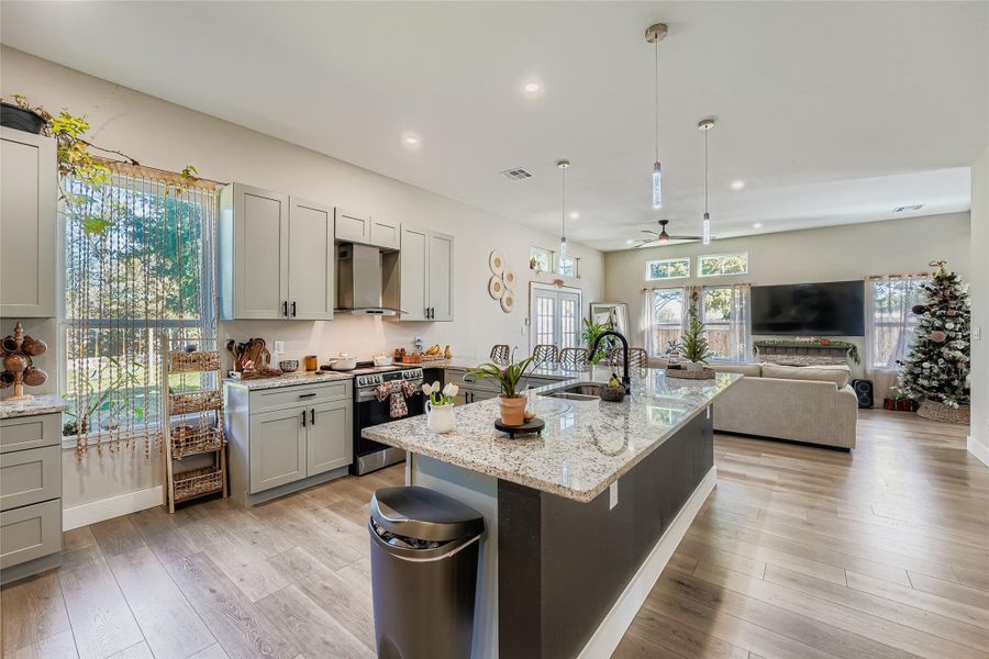 Kitchen with decorative light fixtures, light stone countertops, electric stove, gray cabinetry, and recessed lighting Kitchen with decorative light fixtures, light stone countertops, electric stove, gray cabinetry, and recessed lighting