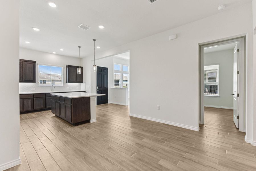 Kitchen featuring decorative light fixtures, a kitchen island, decorative backsplash, dark brown cabinetry, and recessed lighting Kitchen featuring decorative light fixtures, a kitchen island, decorative backsplash, dark brown cabinetry, and recessed lighting