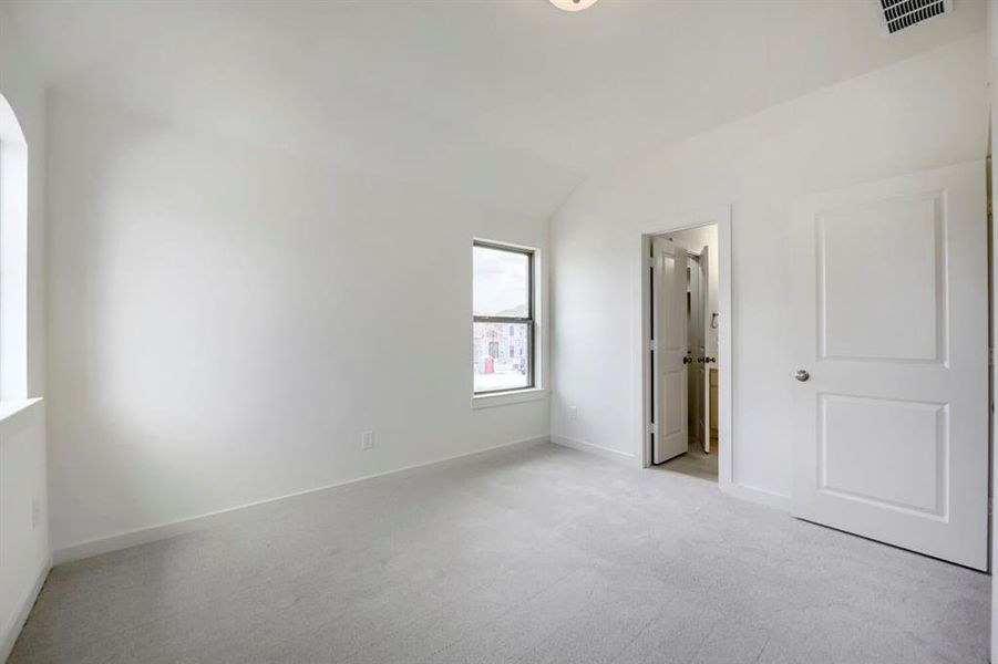 Carpeted room featuring a vaulted ceiling and two windows Carpeted room featuring a vaulted ceiling and two windows