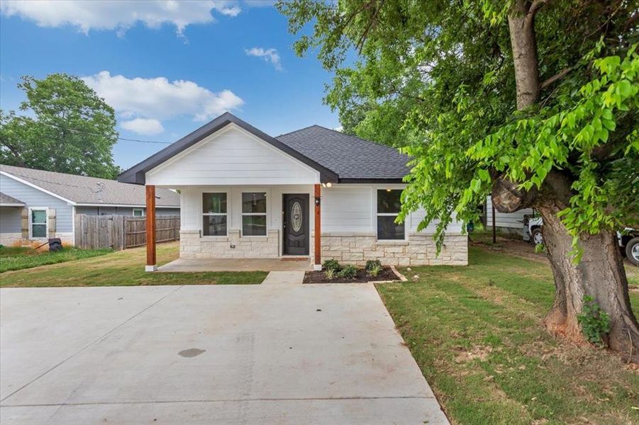 View of front of house featuring a front porch, spacious driveway, and yard