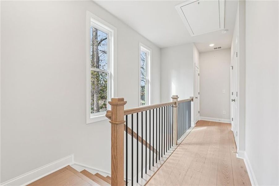 Hall with light wood-type flooring, an upstairs landing, and recessed lighting