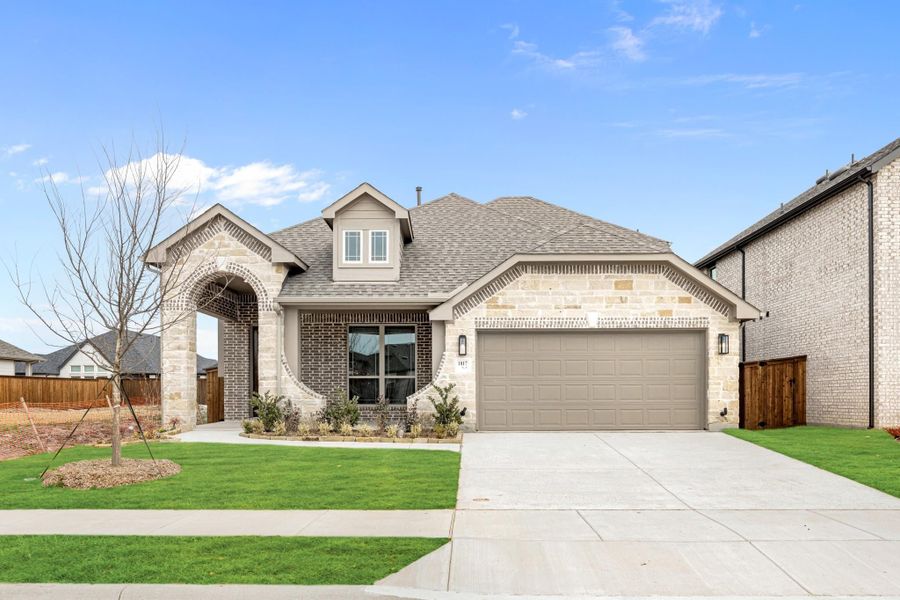 Single-story home with stone and brick exterior, arched entryway, two-car garage, and green front lawn Single-story home with stone and brick exterior, arched entryway, two-car garage, and green front lawn