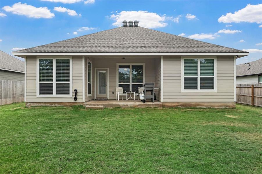 Back of property with a shingled roof and a patio
