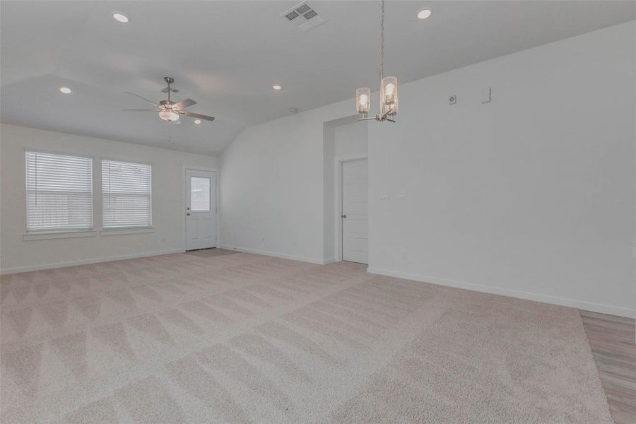 Generously sized and filled with natural light, the living room offers plush carpeting, a ceiling fan, recessed lighting, and backyard access through a full-light rear door. With room for sectional seating and more, it’s a cozy space that connects directly to the covered patio and fenced yard beyond.