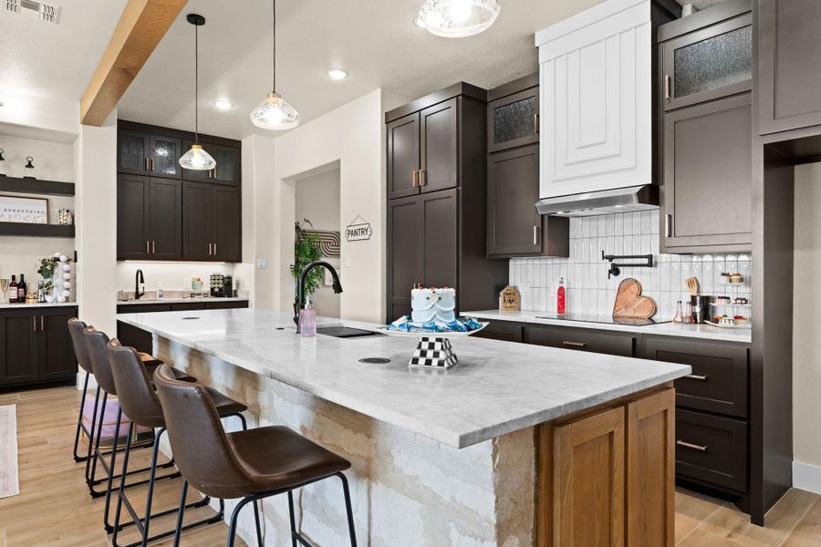 Kitchen with a sink, light wood-type flooring, decorative backsplash, a center island with sink, and a kitchen bar Kitchen with a sink, light wood-type flooring, decorative backsplash, a center island with sink, and a kitchen bar