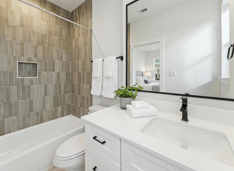 Ensuite bathroom featuring a quartz-topped vanity, matte black fixtures, and a tub-shower combo with warm vertical tile for a modern, spa-inspired finish. *Virtually staged*