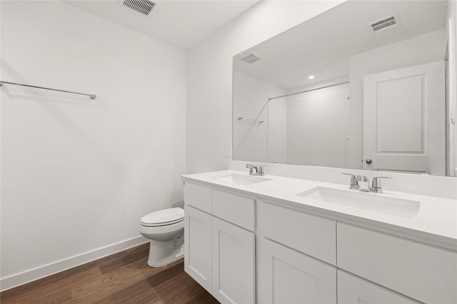 This stylish secondary bath offers a fresh, modern look with clean white finishes, and a sleek vanity with dual sinks. A perfect blend of simplicity and elegance.