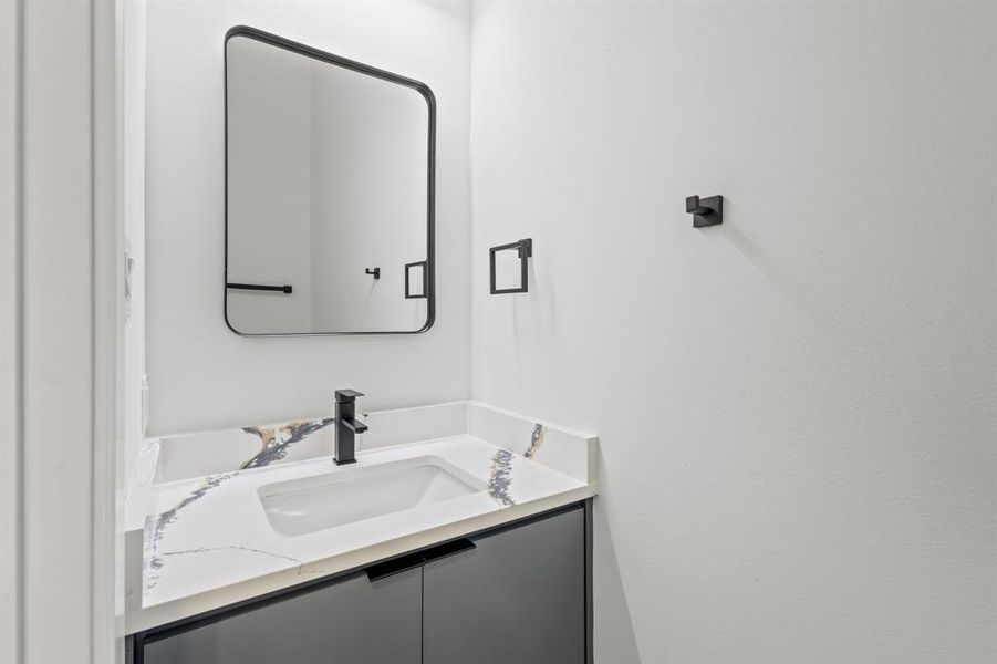 Modern vanity featuring a built-in rectangular sink, white countertop with dark veining, matte black faucet, and dark-toned cabinetry Modern vanity featuring a built-in rectangular sink, white countertop with dark veining, matte black faucet, and dark-toned cabinetry