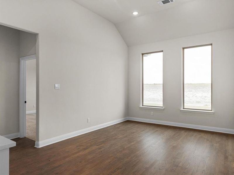 Spare room with dark wood finished floors, vaulted ceiling, and recessed lighting