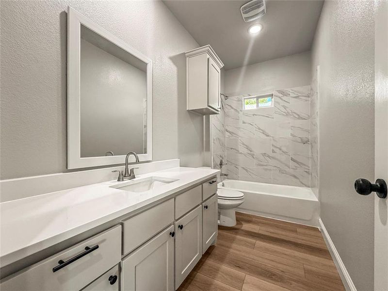 Contemporary bathroom featuring a spacious vanity with an integrated sink, white countertop, and gray shaker-style cabinetry Contemporary bathroom featuring a spacious vanity with an integrated sink, white countertop, and gray shaker-style cabinetry