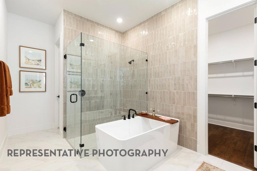 Bathroom with a spacious closet, a freestanding tub, a shower stall, recessed lighting, and tile walls
