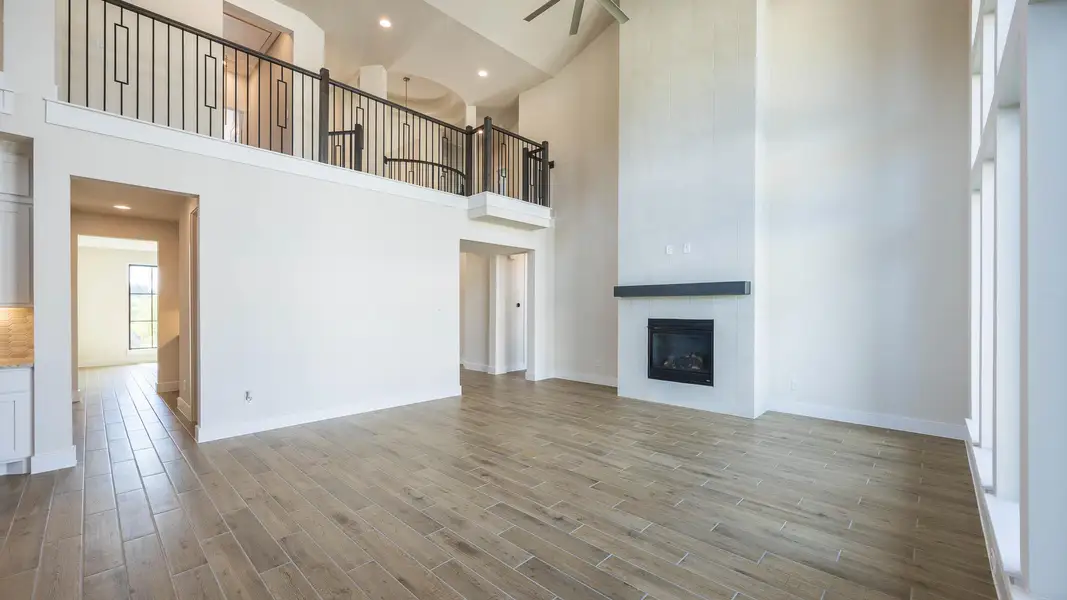 Unfurnished living room with a towering ceiling, light wood-style flooring, a large fireplace, and recessed lighting Unfurnished living room with a towering ceiling, light wood-style flooring, a large fireplace, and recessed lighting