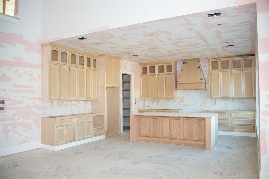 Custom built cabinetry at kitchen complemented by a stunning white oak island with a waterfall edge and matching white oak vent hood for seamless style