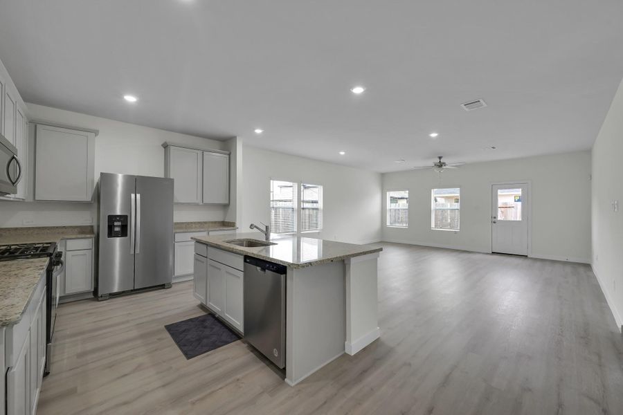 Open-concept kitchen featuring a large island, granite countertops, stainless steel appliances, and updated flooring throughout the main areas. Open-concept kitchen featuring a large island, granite countertops, stainless steel appliances, and updated flooring throughout the main areas.