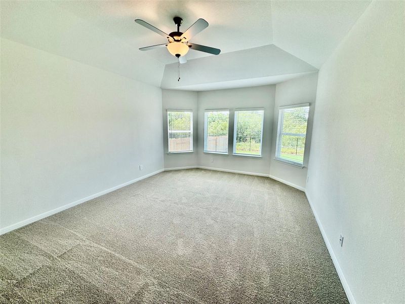 Carpeted empty room featuring lofted ceiling, a ceiling fan, and a textured ceiling Carpeted empty room featuring lofted ceiling, a ceiling fan, and a textured ceiling