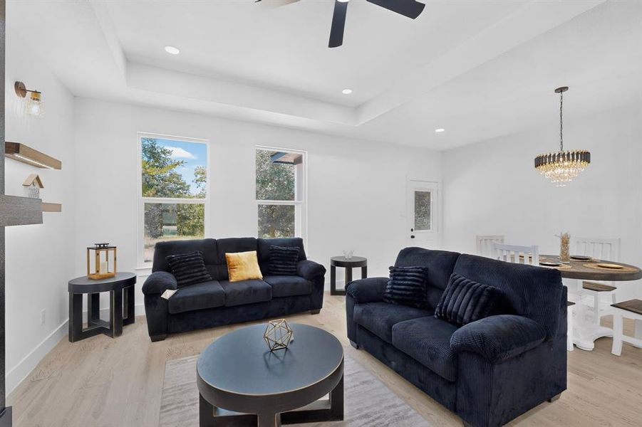 Bright living area featuring wood-finish flooring, recessed lighting, and a tray ceiling