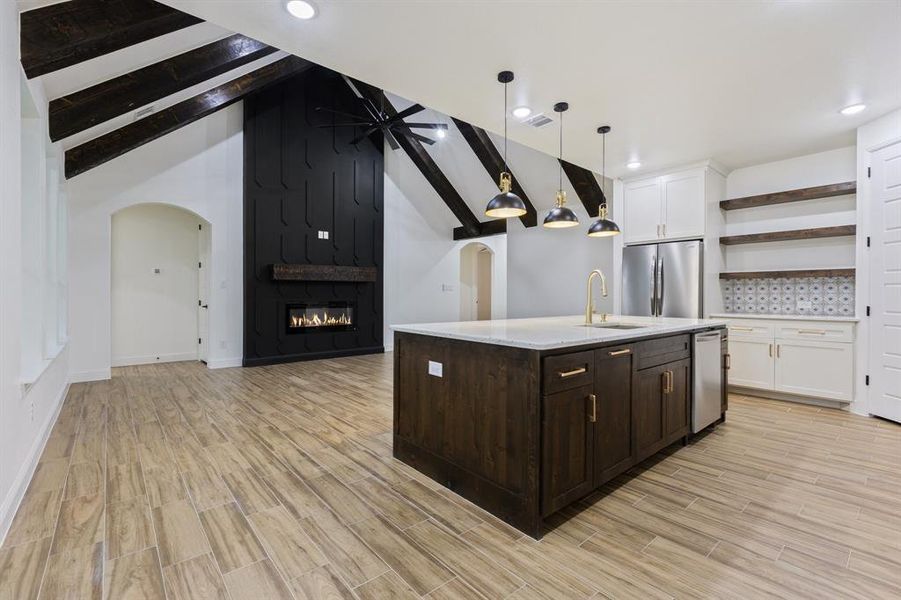 Kitchen featuring appliances with stainless steel finishes, white cabinetry, open shelves, dark brown cabinets, and a large fireplace