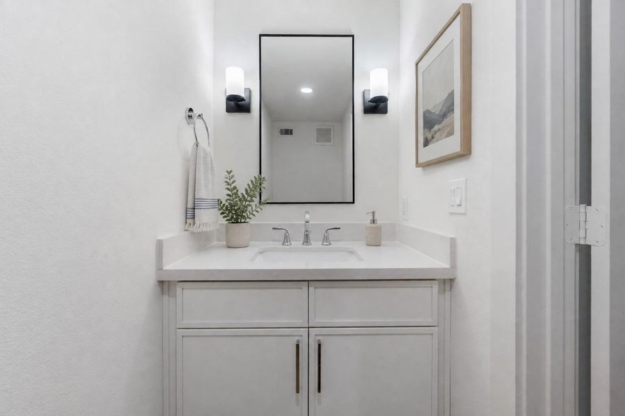 Tucked Away – The powder room is designed to ensure privacy while being convenientlyaccessible. Painted vanity, quartz countertop, undermount porcelain sink, wall mounted faucet,framed mirror flanked by elegant light sconces on both sides.