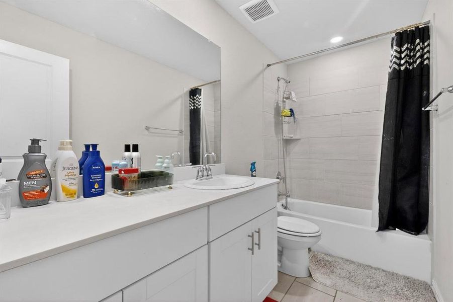 Bathroom with shower / bath combination with curtain, vanity, and light tile patterned flooring Bathroom with shower / bath combination with curtain, vanity, and light tile patterned flooring