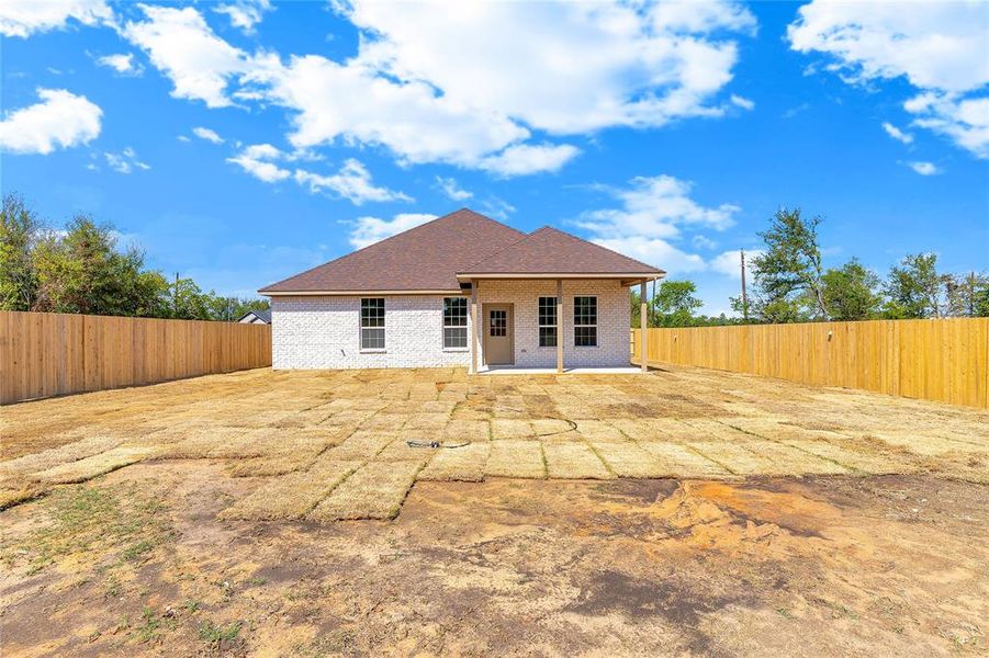 Rear view of property featuring a patio, brick siding, a fenced backyard, and a shingled roof