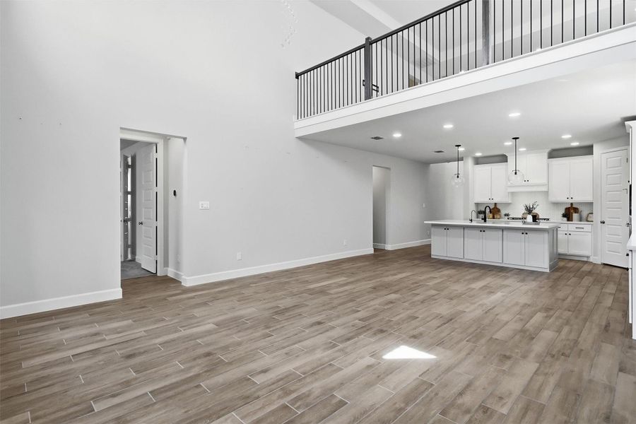 Another perspective showcases the incredible scale of the family room and its direct connection to the kitchen. The dramatic second-story overlook, expansive wall space for statement artwork or media, and open layout provide endless opportunities to personalize this remarkable living area.