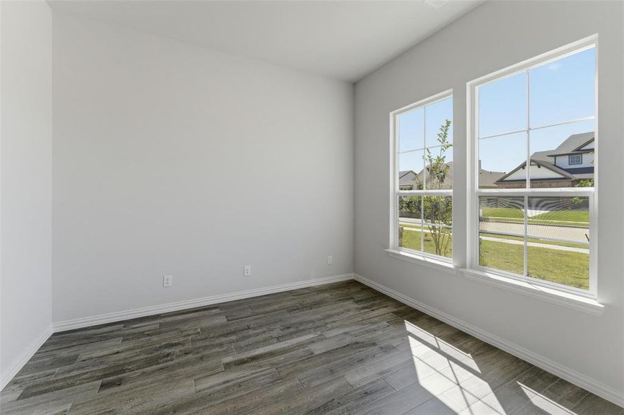 Empty room featuring dark wood finished floors and baseboards