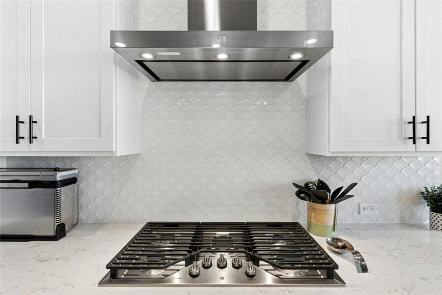 Kitchen view of 5 burner cooktop with modern exhaust system to ceiling