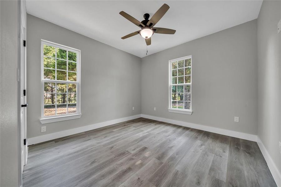 Empty room featuring hardwood / wood-style flooring, plenty of natural light, and ceiling fan