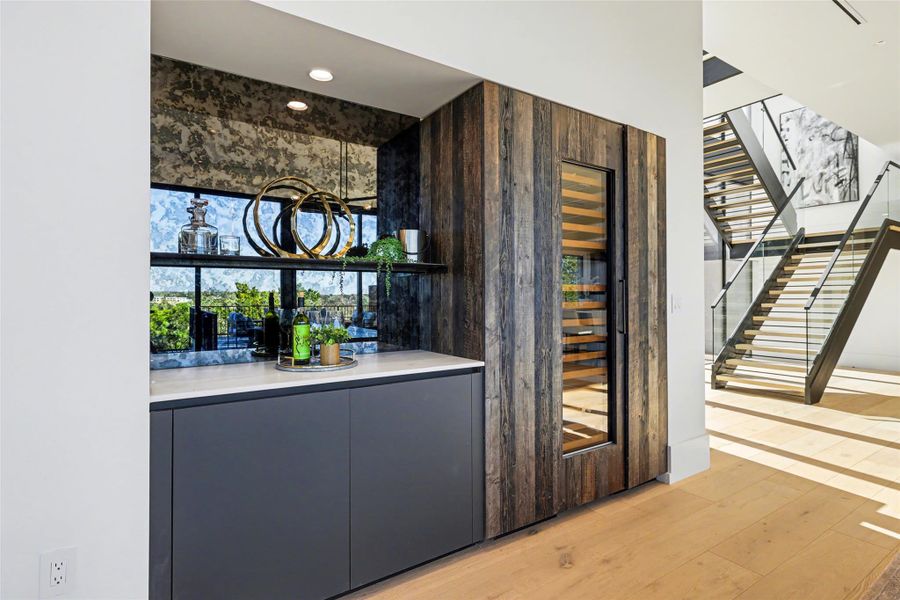 Bar area featuring modern cabinets, gray cabinetry, light wood-style flooring, and healthy amount of natural light