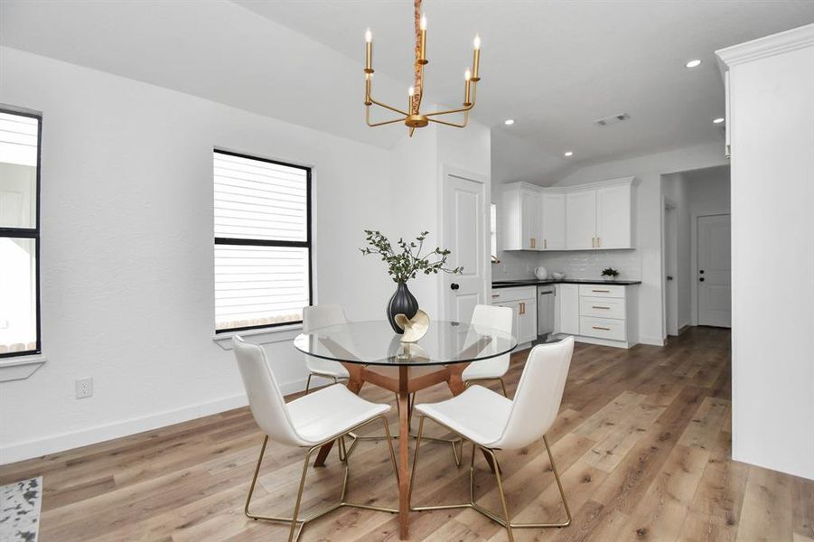 This is a modern kitchen featuring white cabinetry with gold hardware, stainless steel appliances, a gas range, a built-in oven, and a subway tile backsplash. The floors are light wood, and there's ample storage and counter space.