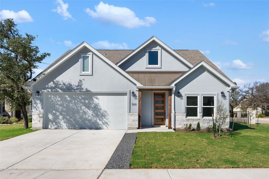 View of front of home with a standing seam roof, a metal roof, stone siding, concrete driveway, and stucco siding