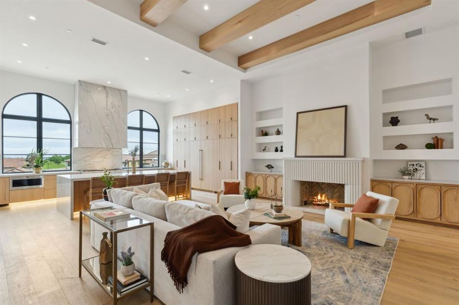 Living area with built in features, white oak wood floors, recessed lighting, a cast stone fireplace, and beamed ceiling Living area with built in features, white oak wood floors, recessed lighting, a cast stone fireplace, and beamed ceiling